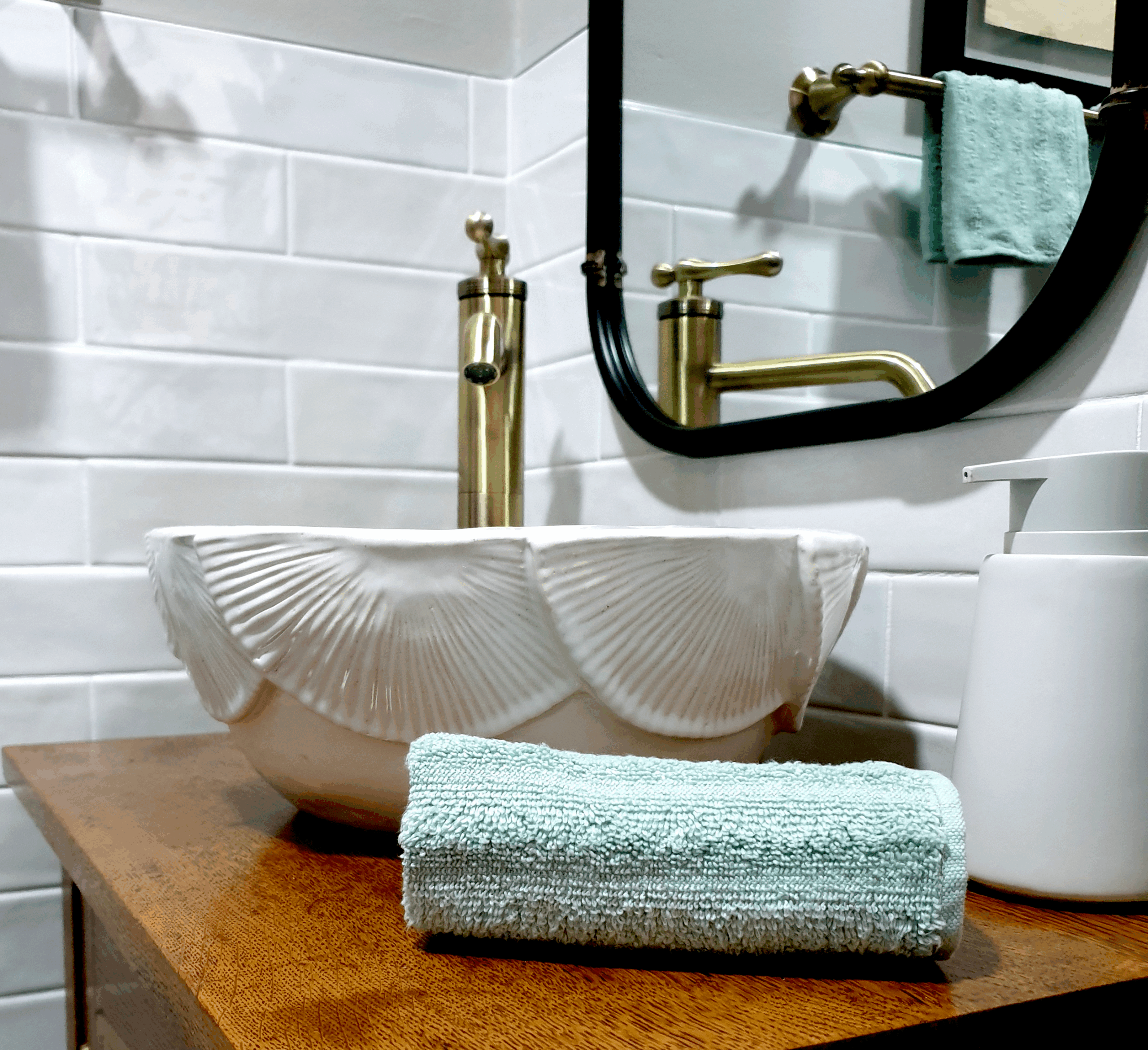 Handcrafted white ceramic vessel basin featuring the Wheel of Time relief pattern, installed on a timber vanity with brass tapware in a contemporary bathroom.