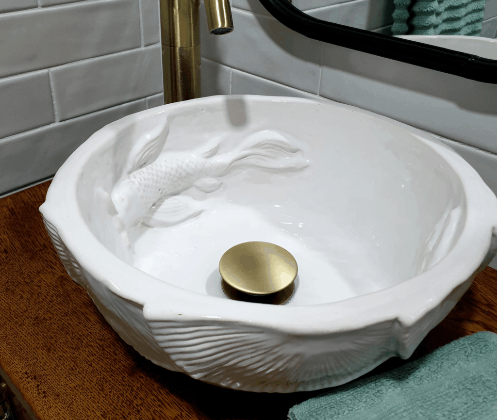 Artisan-made circular white ceramic basin featuring handcrafted koi fish and Lilypad detailing, ideal for elegant bathroom interiors.
