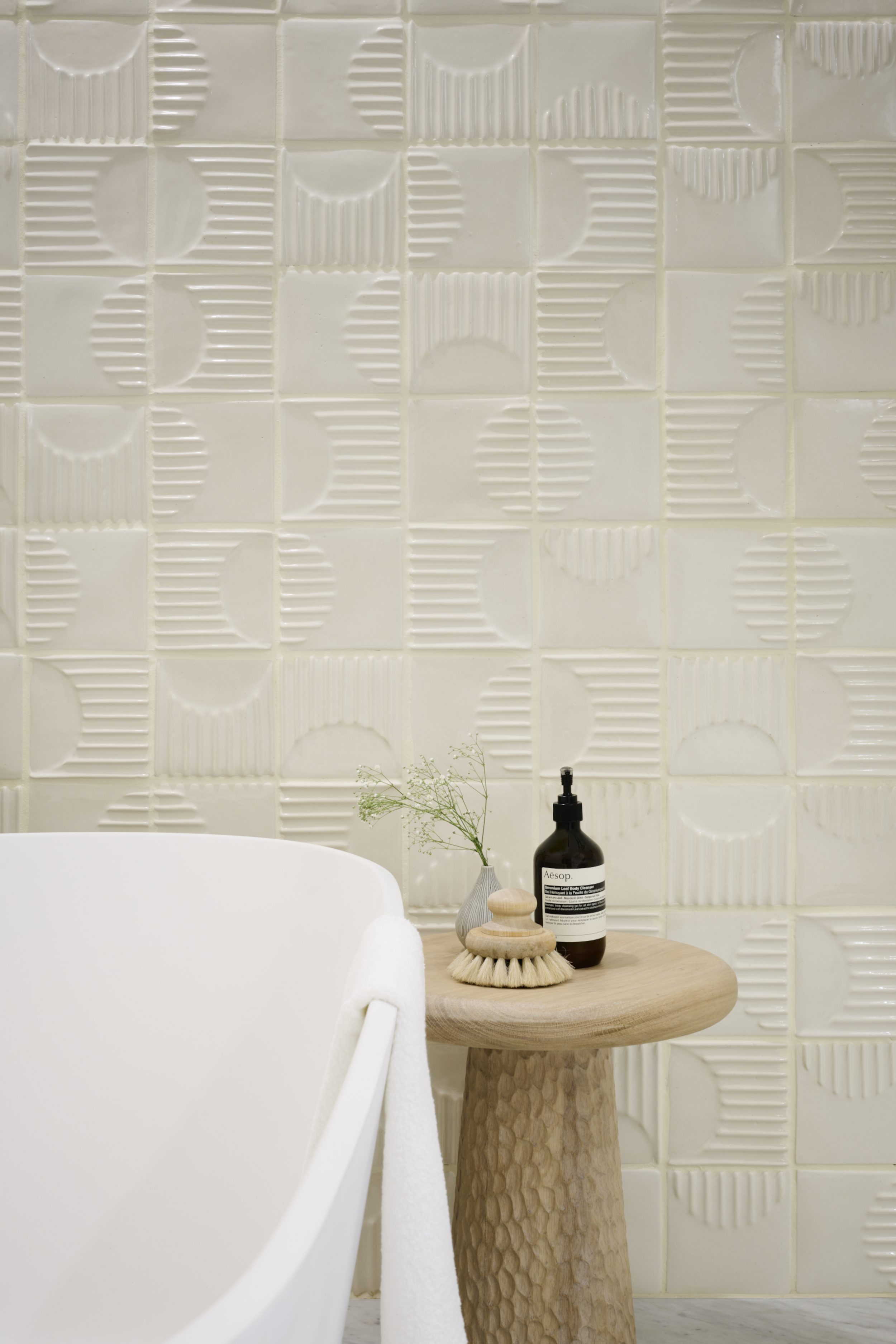 Contemporary bathroom featuring white handcrafted Turning Circles ceramic wall tiles with textured geometric detailing and minimalist styling.