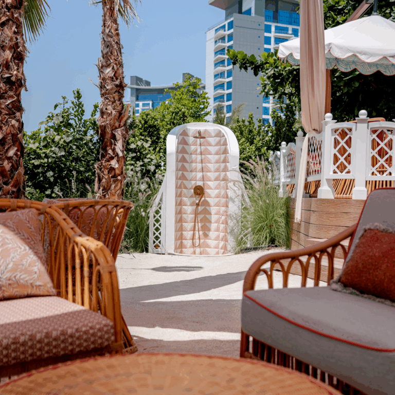 Shadow & Light handmade ceramic tiles in Cement Pink and White installed on an outdoor shower feature, showcasing a geometric textured pattern in a luxury coastal setting.