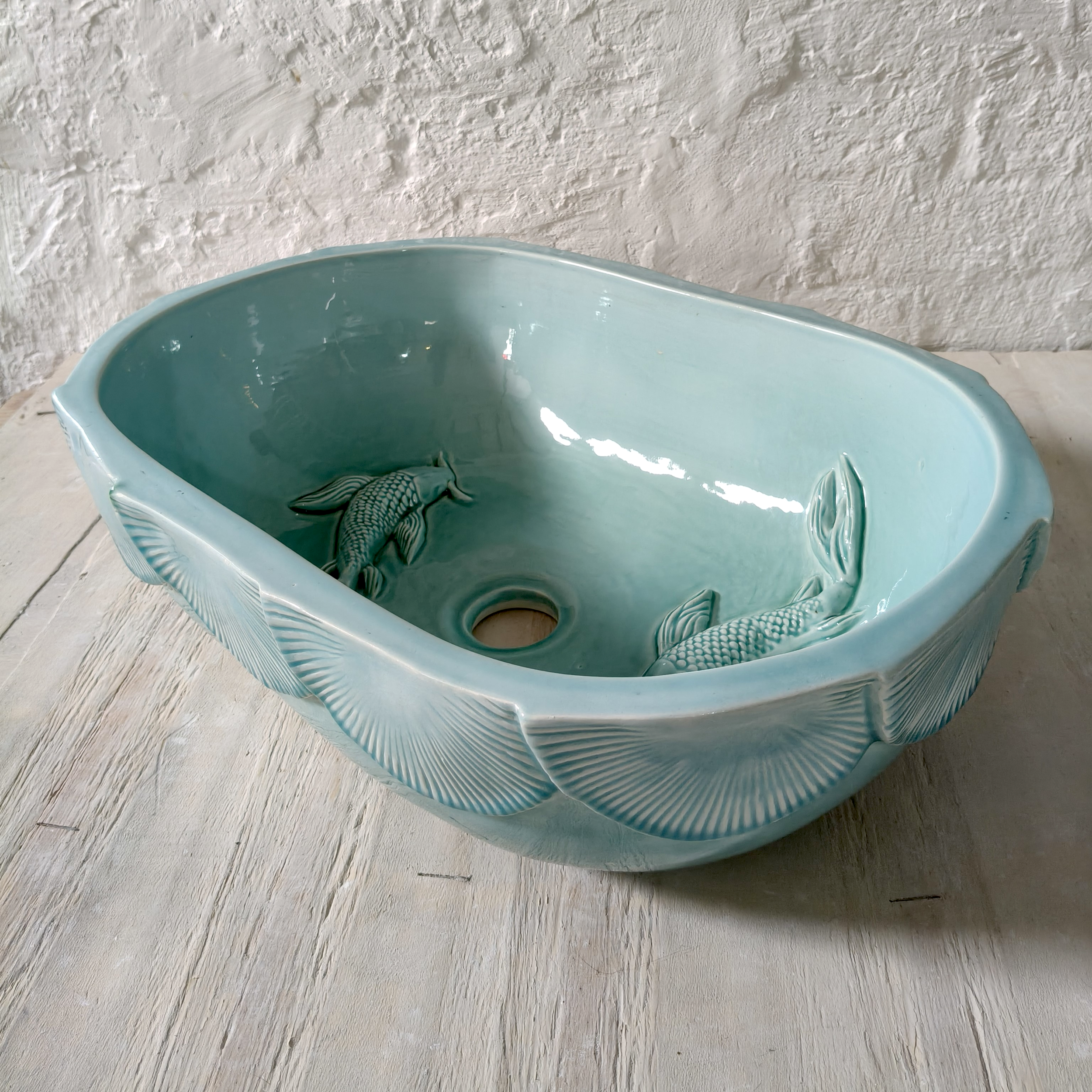 Handcrafted large oval ceramic basin in aqua light turquoise glaze featuring embossed fish and lily motifs with textured scalloped detailing, ideal for luxury bathrooms and coastal-inspired interiors.