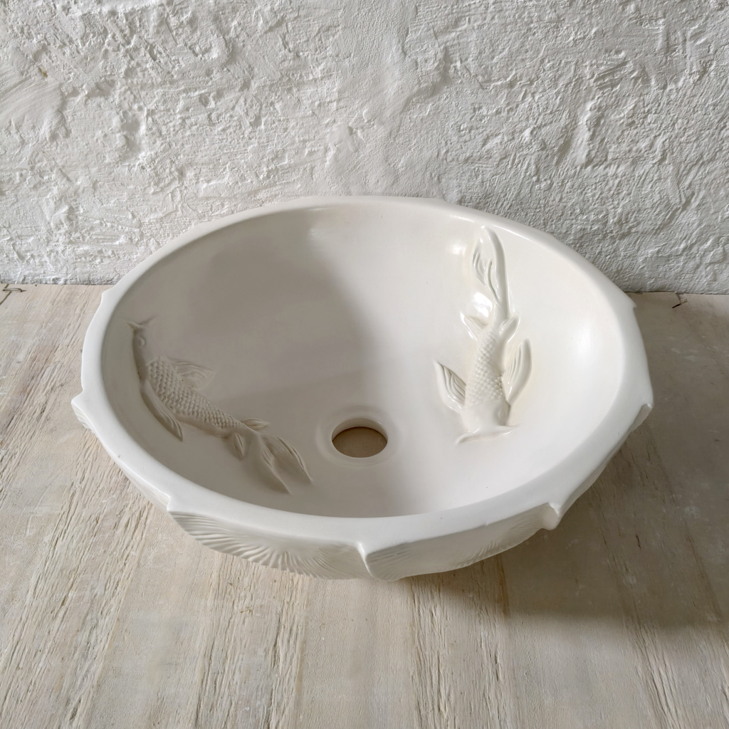 Artisan-made round white ceramic bathroom basin with raised fish designs and decorative scalloped texture, perfect for spa-inspired and contemporary bathroom spaces.