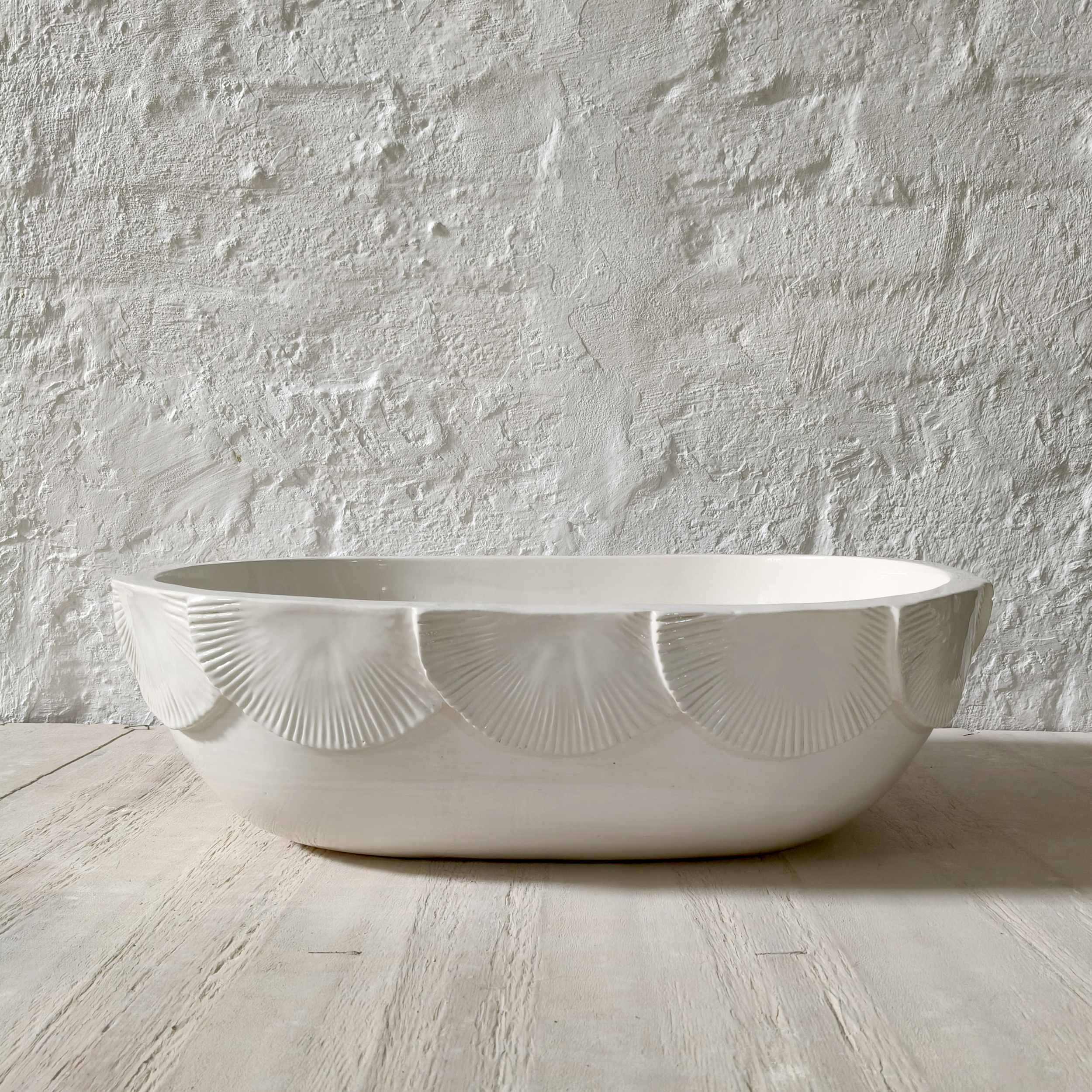 Handmade artisan white ceramic wash basin with decorative shell-inspired scalloped edge design, ideal for modern bathroom vanities and spa-inspired spaces.