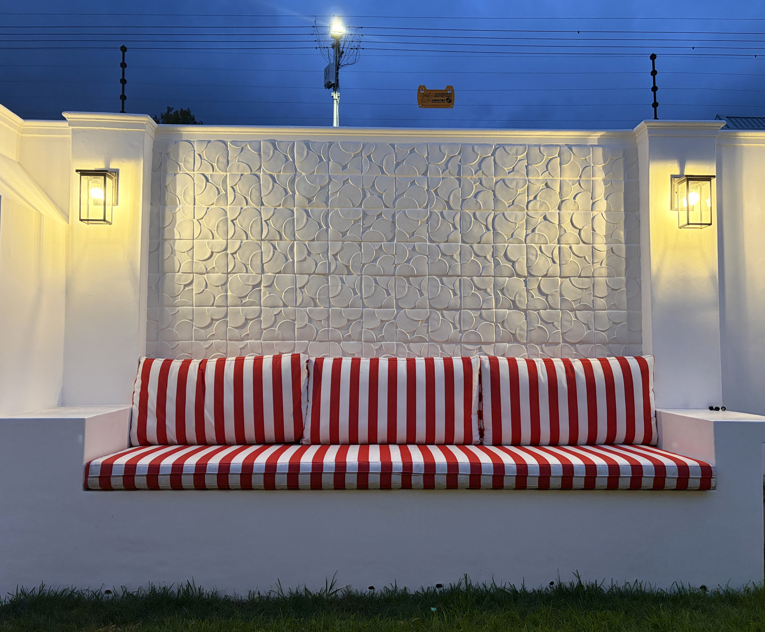 Outdoor seating area with handcrafted ceramic feature tiles, warm lighting, and striped cushions.